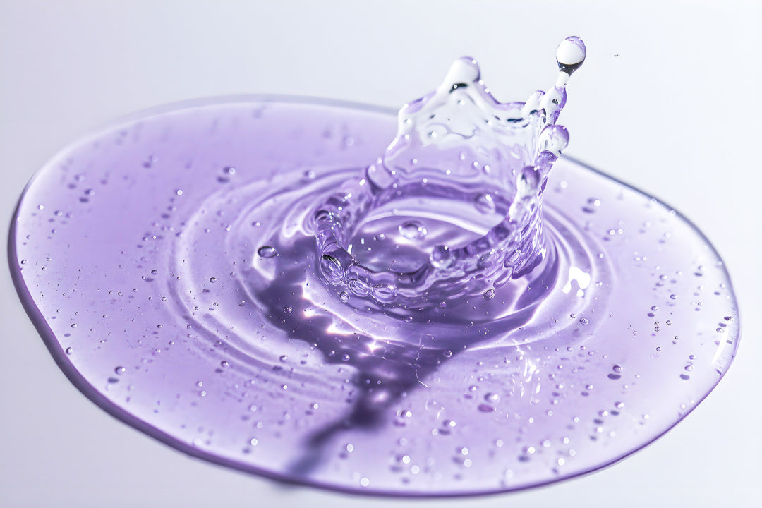 Nexa Serum droplet creating a circular splash on a reflective surface with a purple tint.
