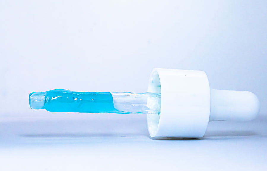 Dropper with blue liquid on a light gray background