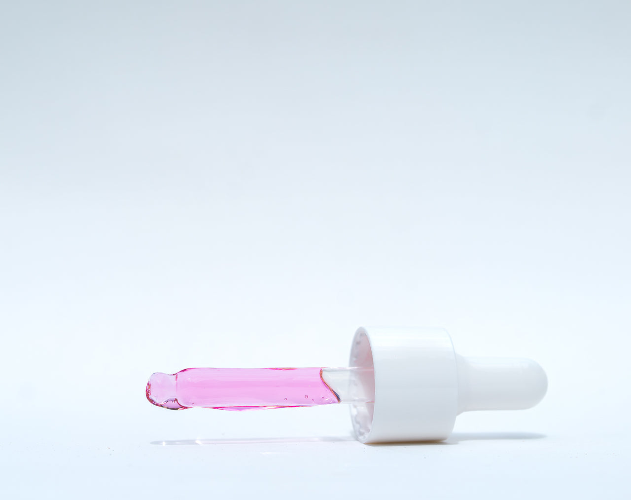 White and pink cosmetic product on a light gray background